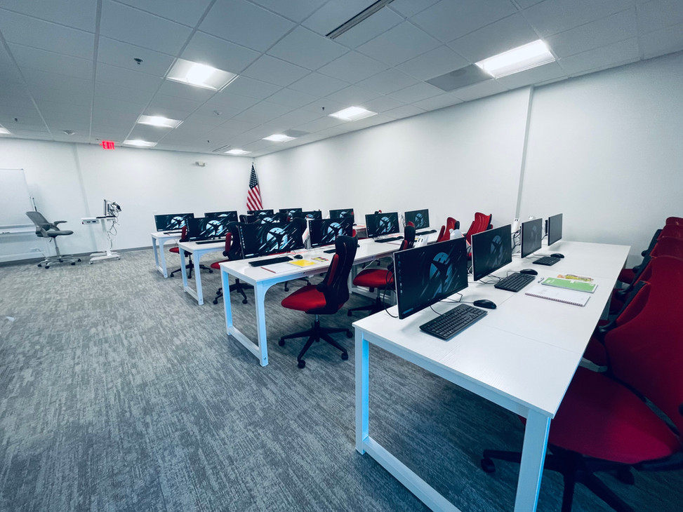Flight Innovation classroom with rows of white desks, computer screens, and red chairs