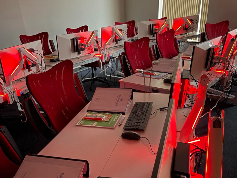 Monitors and reference books at a Flight Innovation classroom workstation
